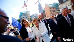 German President Joachim Gauck (R) and Chancellor Angela Merkel (C) meet wellwishers in the streets of Frankfurt, Germany, October 3, 2015. Germany's political leaders celebrate the country's 25th anniversary since the reunification of East and West Germa