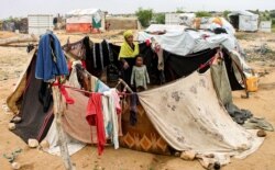 FILE - A woman and child sit together in an enclosure made from fabrics at a make-shift camp for displaced Yemenis in the northern Hajjah province, Dec. 16, 2019.