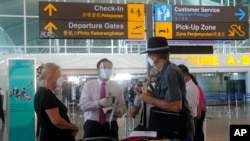 Petugas bandara memeriksa warga Australia setibanya di bandara internasional Ngurah Rai, Bali, 18 Agustus 2021. (AP Photo/Firdia Lisnawati)