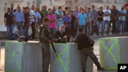 Polisi Israel memeriksa kartu identitas warga Palestina saat mereka keluar dari distrik Issawiyeh yang merupakan kediaman warga etnis Arab di Yerusalem, Minggu (18/10)/