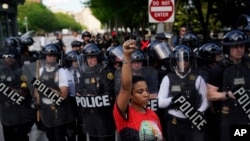 FILE - A demonstrator raises her fist to protest the death of George Floyd, near the White House, in Washington, May 30, 2020. Floyd, an African American, died after being restrained by Minneapolis police officers, triggering nationwide protests.