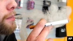 FILE - A sales associate demonstrates the use of an electronic cigarette and the smoke-like vapor that comes from it, in Aurora, Colorado, March 2, 2011.