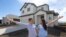 In this April 27, 2019, photo, millennials Andy and Stacie Proctor stand in front of their new home in Vineyard, Utah. 