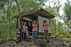 FILE - Elementary school students, aiming to study online using their smartphones, search for a better internet signal than in their village, on Temulawak hill in Yogyakarta, Indonesia, May 8, 2020.