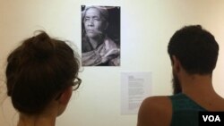 Visitors take a closer look at another fortune teller, Seim Chantha, holding three smoked cigarettes in his hand.