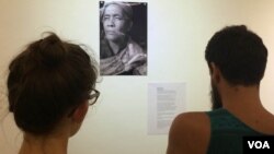 អ្នក​​ទស្សនា​ពិនិត្យ​មើល​រូបថត​គ្រូ​ទាយ Seim Chantha។ (ផន បុប្ផា/VOA)