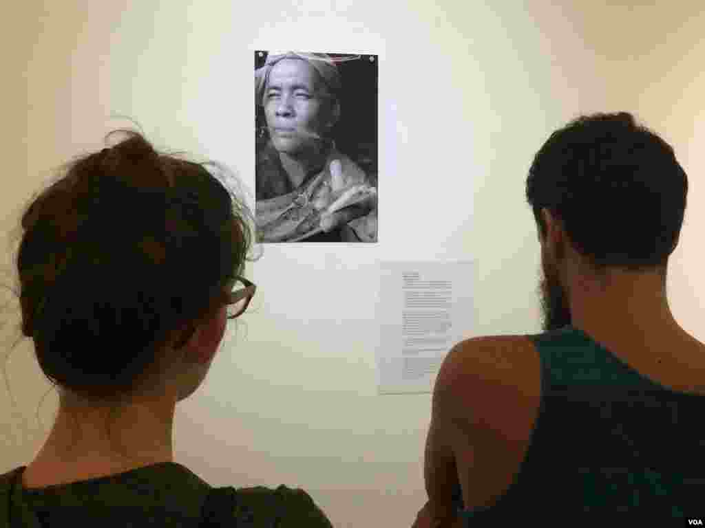 Visitors take a closer look at another fortune teller, Seim Chantha, holding three smoked cigarettes in his hand.