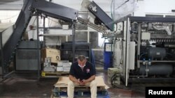 Seorang pekerja asal Palestina tampak menggunakan telepon genggam miliknya di pabrik minuman ringan Pepsi di Gaza pada 21 Juni 2021. (Foto: Reuters/Mohammed Salem)