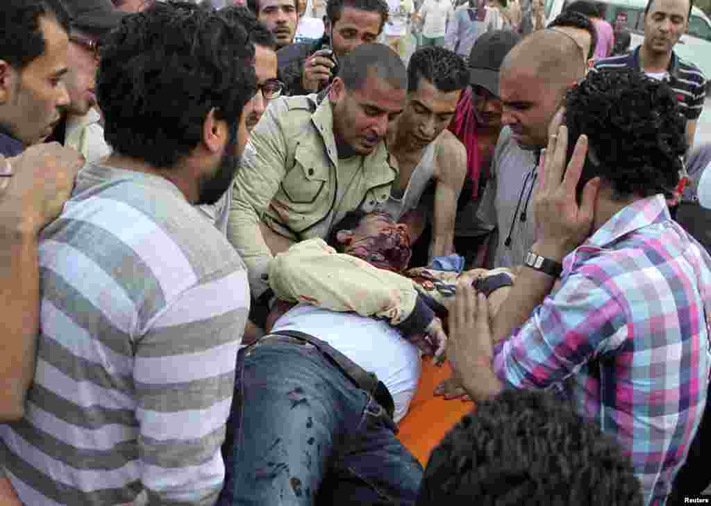 Coptic Christians help a man who was injured by a bullet from a cartridge gun, inside the main cathedral in Cairo, during clashes with Muslims, April 7, 2013. 
