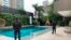 In this photo distributed by Colombia's Attorney Generals Office, officials pose with their backs to the camera by a pool on a property allegedly belonging to Alex Saab in Barranquilla, Colombia, July 22, 2020.