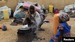 A displaced girl cooks at an arena for traditional wrestling in the town of Diffa in southeastern Niger June 20, 2016. 