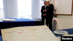FILE - Officials stand near a display of documents from the recovered diary of Nazi leader Alfred Rosenberg during a news conference at the Department of Homeland Security office in Wilmington, Delaware, June 13, 2013. 