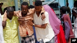 Somalis help a civilian who was wounded in suicide bomb attack at a military base in Mogadishu, Somalia, June, 15, 2021.