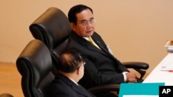 泰国总理巴育(上图)在议会特别会议上与副总理巴威交谈。（2020年10月26日）