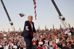 U.S. President Donald Trump throws a face mask from the stage during a campaign rally, his first since being treated for the coronavirus disease (COVID-19), at Orlando Sanford International Airport in Sanford, Florida, Oct. 12, 2020.