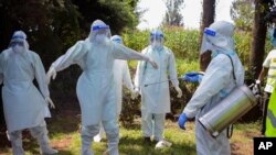 FILE - Health workers wearing protective suits prepare to bury coronavirus victim Dr. Doreen Adisa Lugaliki, at her funeral in Ndalu, Bungoma county, Kenya, July 13, 2020.