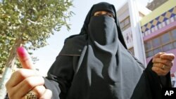 A veiled Egyptian woman displays her ink-stained fingertip after casting her vote for a referendum on constitutional amendments at a polling station in Cairo, Egypt, March 19, 2011 (file photo)