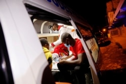 FILE - Medics examine a pregnant woman in an ambulance during the coronavirus night curfew in Nairobi, Kenya, June 19, 2020.