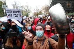Restaurant workers protest a tighening of coronavirus restictions, including lockdowns on weekends, in Kyiv, Ukraine, Nov. 11, 2020. The sign reads "Weekend lockdowns put a million people out of work."