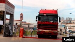 Workers in protective suits are seen by a truck at a plant of pork processor Henan Shuanghui Investment & Development, a subsidiary of WH Group, following a discovery of pigs infected by the African swine fever, in Zhengzhou, Henan, China, Aug. 17, 2018.