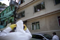 Residents watch water utility workers from CEDAE disinfecting the Vidigal favela in an effort to curb the spread of the new coronavirus in Rio de Janeiro, Brazil, April 24, 2020.