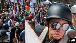 FILE - A white nationalist demonstrator with a helmet and shield walks into Lee Park in Charlottesville, Va., Aug. 12, 2017.