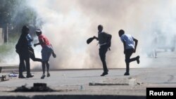 Sejumlah demonstran berlari saat petugas menembakkan gas air mata dalam aksi demo di Cape Town, Afrika Selatan, pada 7 Agustus 2023. (Foto: Reuters/Esa Alexander)