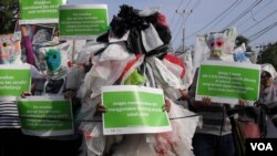 Para aktivis lingkungan Solo membalut seluruh tubuhnya dengan kantong-kantong plastik dalam aksi di sepanjang jalan Slamet Riyadi di Solo, hari Minggu pagi (15/7).