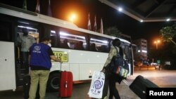 FILE - A migrant domestic worker from Africa pulls her luggage toward a bus that will take her with others to the airport to travel back to their home countries, in a Beirut suburb, Lebanon, Oct. 5, 2020.