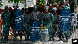 Cambodian riot police officers stand guard behind barbed wire as they block entry to Freedom Park, in Phnom Penh, Cambodia, July 15, 2014. 