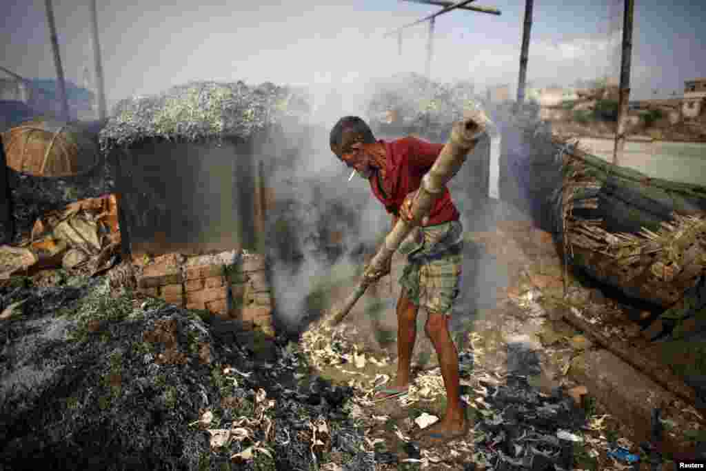Seorang pekerja memproses sampah untuk dijadikan makanan unggas di pinggir sungai Buriganga, Dhaka, Bangladesh.