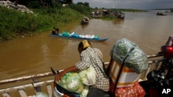 FILE PHOTO - A vendor, foreground, stands on a ferry together with his goods before crossing the Mekong river in Dei Edth village at the outskirt of Phnom Penh, Cambodia, Wednesday, July 22, 2020. (AP Photo/Heng Sinith)