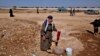An elderly Syrian woman, who fled her home due to government shelling, washes her laundry in tub, as she takes refuge at Bab Al-Salameh crossing border near the Syrian town of Azaz, September 13, 2012. 