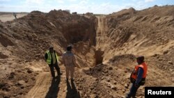 FILE - Rescue workers and a member of Palestinian security forces loyal to Hamas, stand while searching for missing or dead militants after Israel blew up a cross-border tunnel, in Khan Younis in the southern Gaza Strip, Nov. 3, 2017.