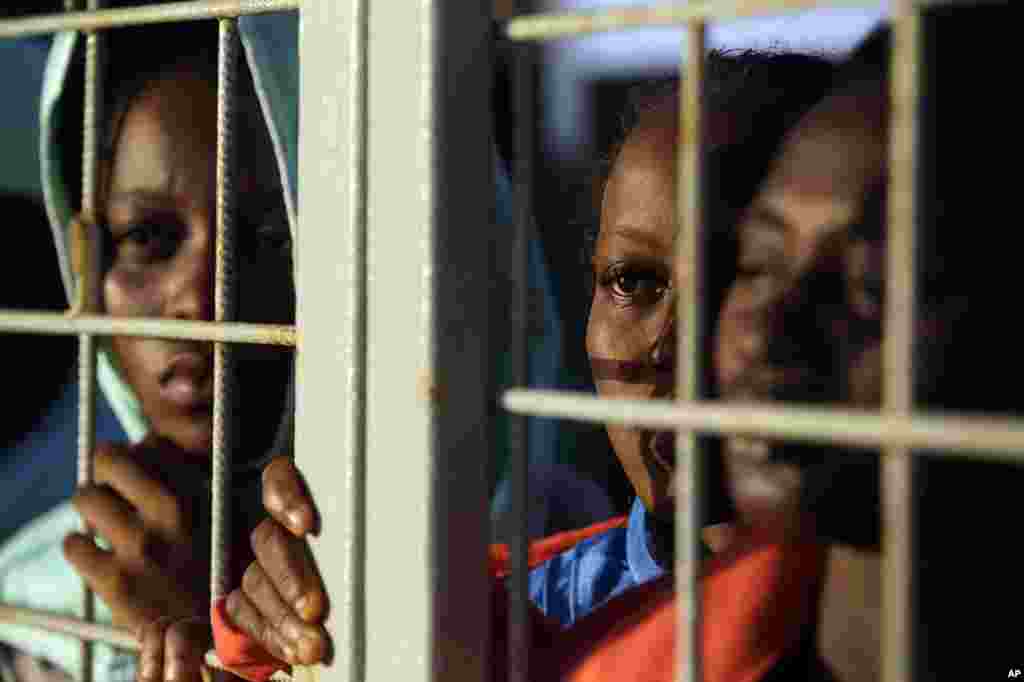 Para migran yang diselamatkan dari pantai Libya mengintip dari gerbang kapal Norwegia Siem Pilot, untuk melihat pulau Sardinia saat mengarungi laut Mediterania menuju pelabuhan Cagliari, Italia (3/9). (AP/Gregorio Borgia)