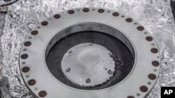 美国宇航局2023年10月11日提供的照片显示了奥西里斯-雷克斯样本收集器的外部，右边中间是来自小行星贝努的材料。（美国宇航局通过美联社发布）