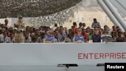 Migrants arrive on the British vessel HMS Enterprise before disembarking in the Sicilian harbour of Catania, Italy, Oct. 6, 2015.