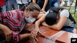 Women cry over the coffin of a relative, a victim of a deadly avalanche due to heavy rains, during a mass burial in Mocoa, Colombia, April 3, 2017.