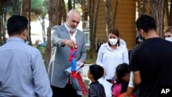 Premijer Albanije Edi Rama pruža poklon dečaku tokom posete smeštaju za izbeglice iz Avganistana u Golemu, 27. avgusta 2021.