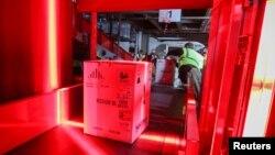 Boxes containing Pfizer's COVID-19 vaccine are unloaded from air shipping containers and scanned at UPS Worldport, in Louisville, Kentucky, December 13, 2020. (Michael Clevenger/Pool via REUTERS)