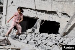 Seorang gadis Palestina berjalan di dekat bangunan yang rusak pasca serangan udara Israel di kamp Jenin di Tepi Barat yang diduduki Israel, 18 Mei 2024. (Foto: REUTERS/Raneen Sawafta)