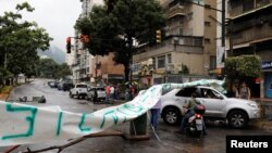 A car and a motorcyclist pass through a barricade during a rally against Venezuelan President Nicolas Maduro's government in Caracas, July 19, 2017. (REUTERS/Carlos Garcia)