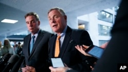 FILE - Republican Senator Richard Burr, right, chairman of the Senate Intelligence Committee, and Democratic Senator Mark Warner, committee vice chair, speak to the media on Capitol Hill in Washington, Sept. 26, 2019. 