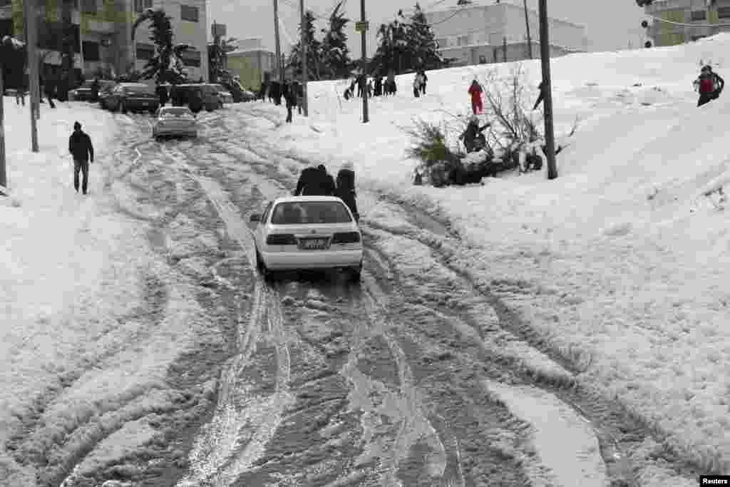 People play with snow after a heavy snowstorm in Amman, Dec. 13, 2013. 