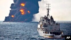 In this photo provided by China's Ministry of Transport, a rescue ship sails near the burning Iranian oil tanker Sanchi in the East China Sea off the eastern coast of China, Jan. 14, 2018. 
