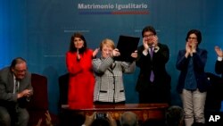 Chile's President Michelle Bachelet holds up a portfolio containing her signed proposal for a same-sex marriage bill at La Moneda presidential palace in Santiago, Chile, Aug. 28, 2017.