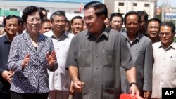 Cambodian Prime Minister Hun Sen, center, cuts the ribbon with Chinese Ambassador to Cambodia Bu Jianguo, left, during the inauguration ceremony of a friendship bridge between Cambodia and China in Takhmao, Kandal provincial town, south of Phnom Penh, Cambodia, Monday, Aug. 3, 2015. The bridge across the Tonle Bassac River opened to the public on Monday. (AP Photo/Heng Sinith)