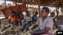 FILE - Women shell maize in the Malembo Village in the Traditional Authority (TA) Khongoni in Lilongwe District, Malawi, May 16, 2019,