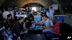 Anggota Komite Independen Pemilu Afganistan mengecek surat suara untuk diaudit di kantor Komisi Pemilu di Kabul (18/7/2014). 
