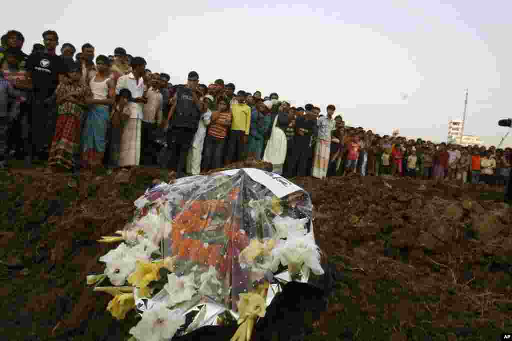 Hundreds of Bangladeshi mourners watch as the bodies of victims of Saturday&#39;s fire in a garment factory are buried in Dhaka, Bangladesh, November 27, 2012. 